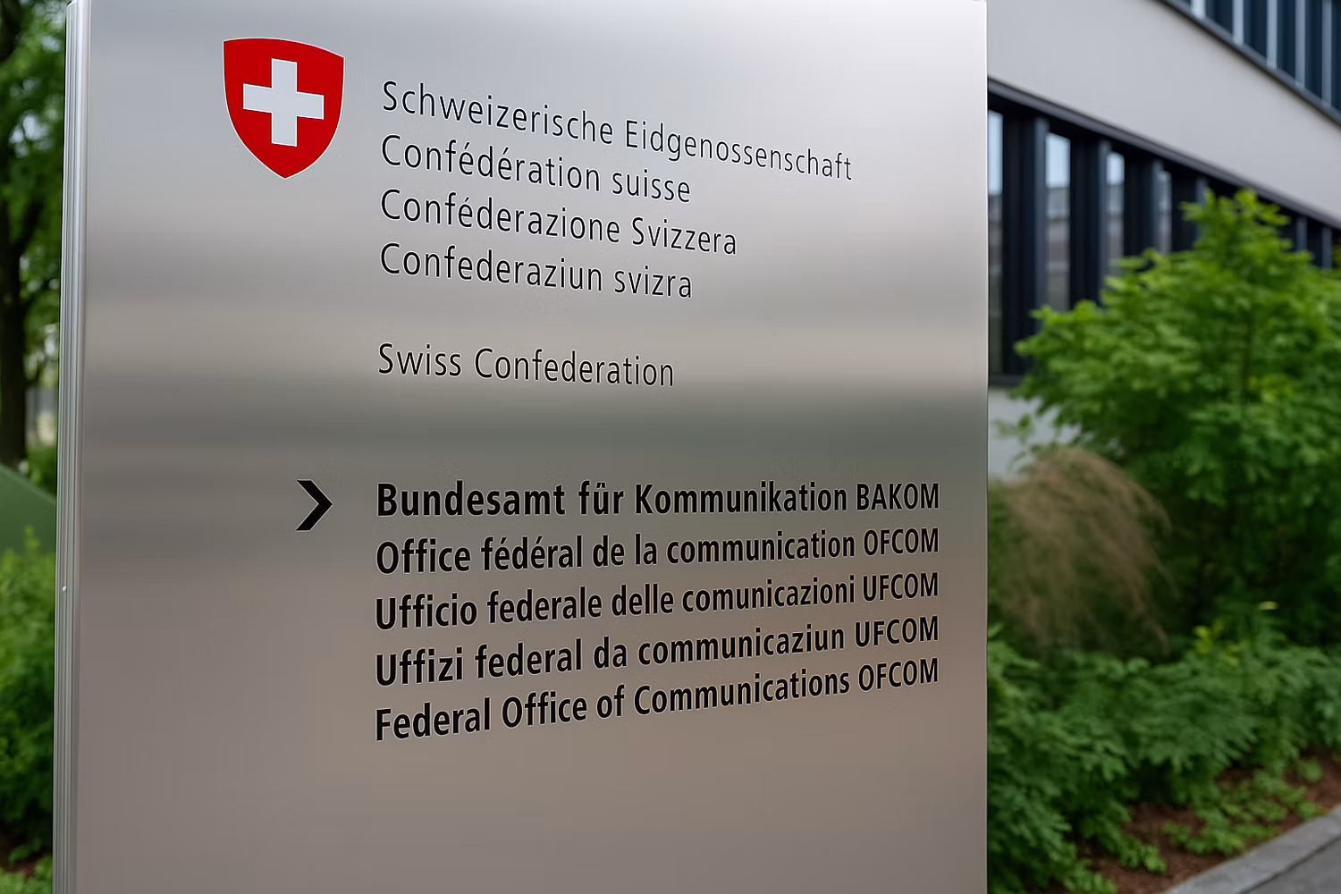 Schild mit der Aufschrift «Bundesamt für Kommunikation BAKOM» vor dem BAKOM-Gebäude